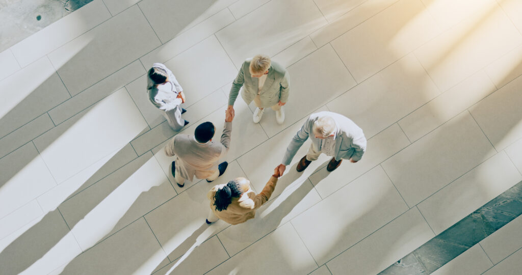 A group handshake and welcome together and meeting in corridor for partnership.
